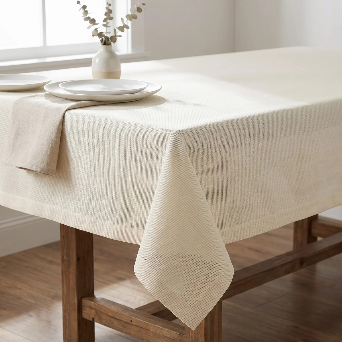 Mantel de tela Granité Premium marfil puesto en una mesa de comedor de madera