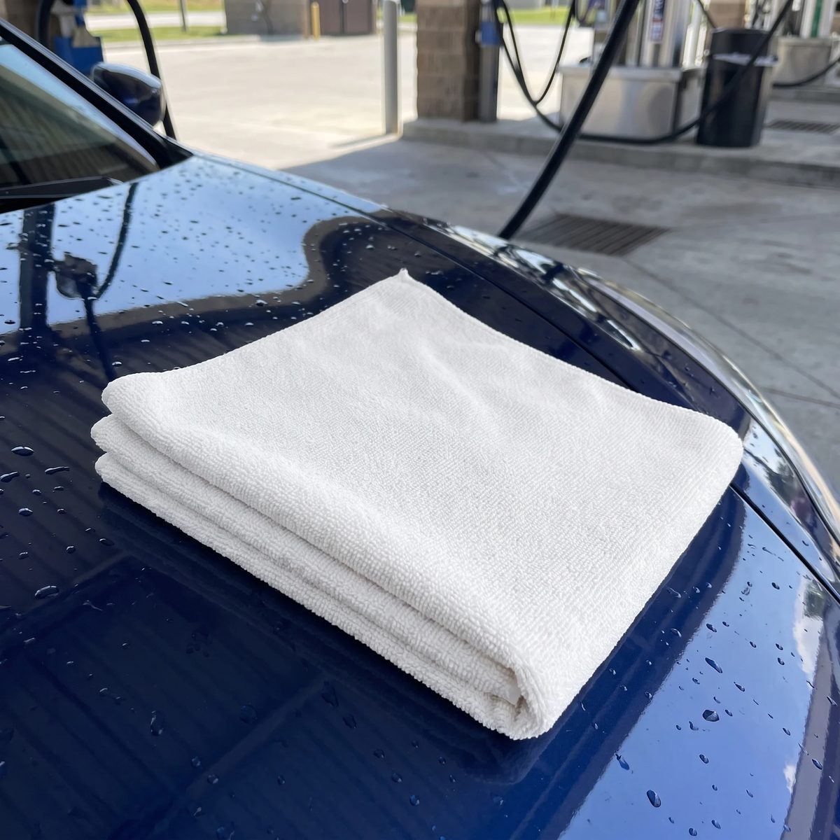 Paño de microfibra blanco doblado sobre el capó de un carro recién lavado