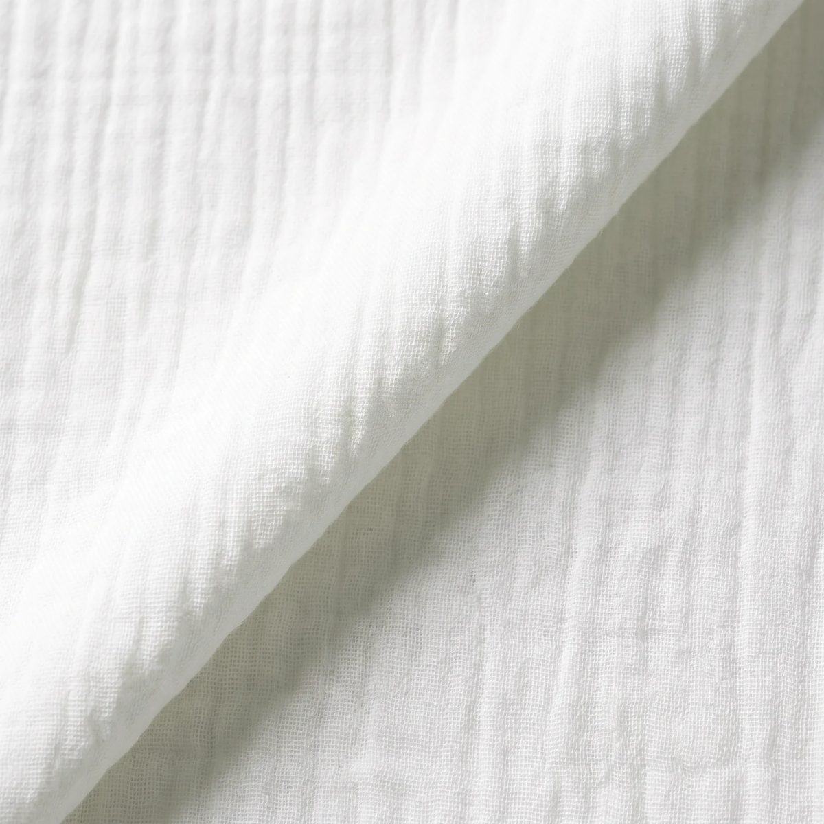 Acercamiento al tejido de la muselina de algodón blanco: las dos capas de gasa y su textura arrugada