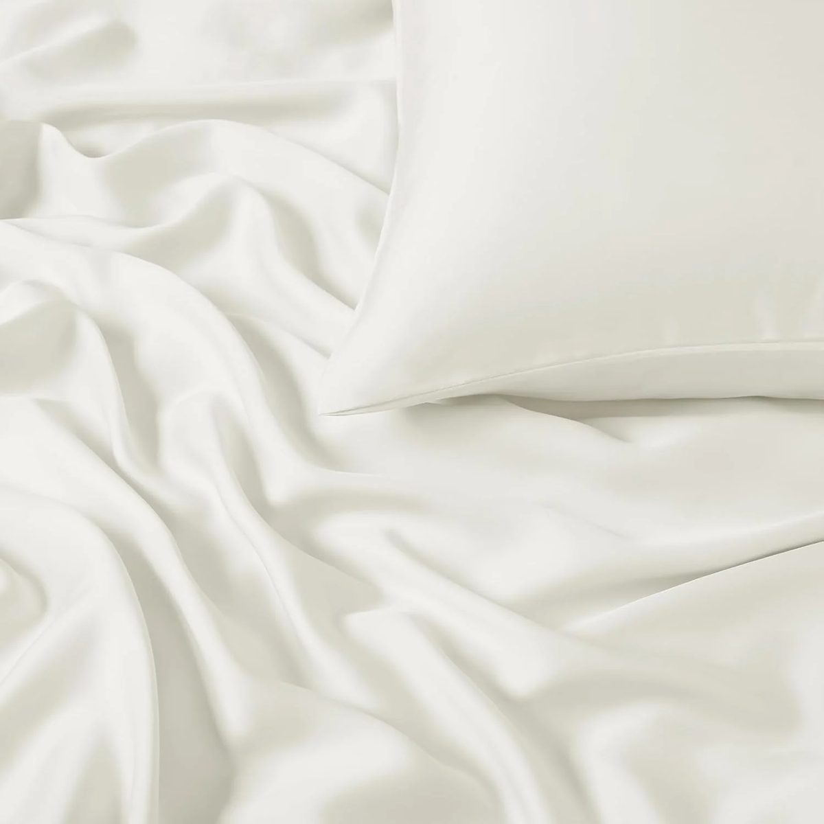 Tencel de Algodón color marfil, extendida sobre una cama junto a una almohada