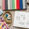 Mesa de trabajo con diversas telas y herramientas de costura, representando ideas para negocios rentables con telas.