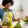 Persona luciendo un delantal de cocina reversible hecho a mano con telas estampadas y de color sólido, mostrando un proyecto DIY con estilo realizado con la guía de Textti de Cómo Hacer un Delantal de Cocina Reversible.