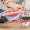 Manos de adulto sosteniendo una prenda de ropa infantil que claramente ha encogido, ilustrando el problema de por qué se encoge la ropa.